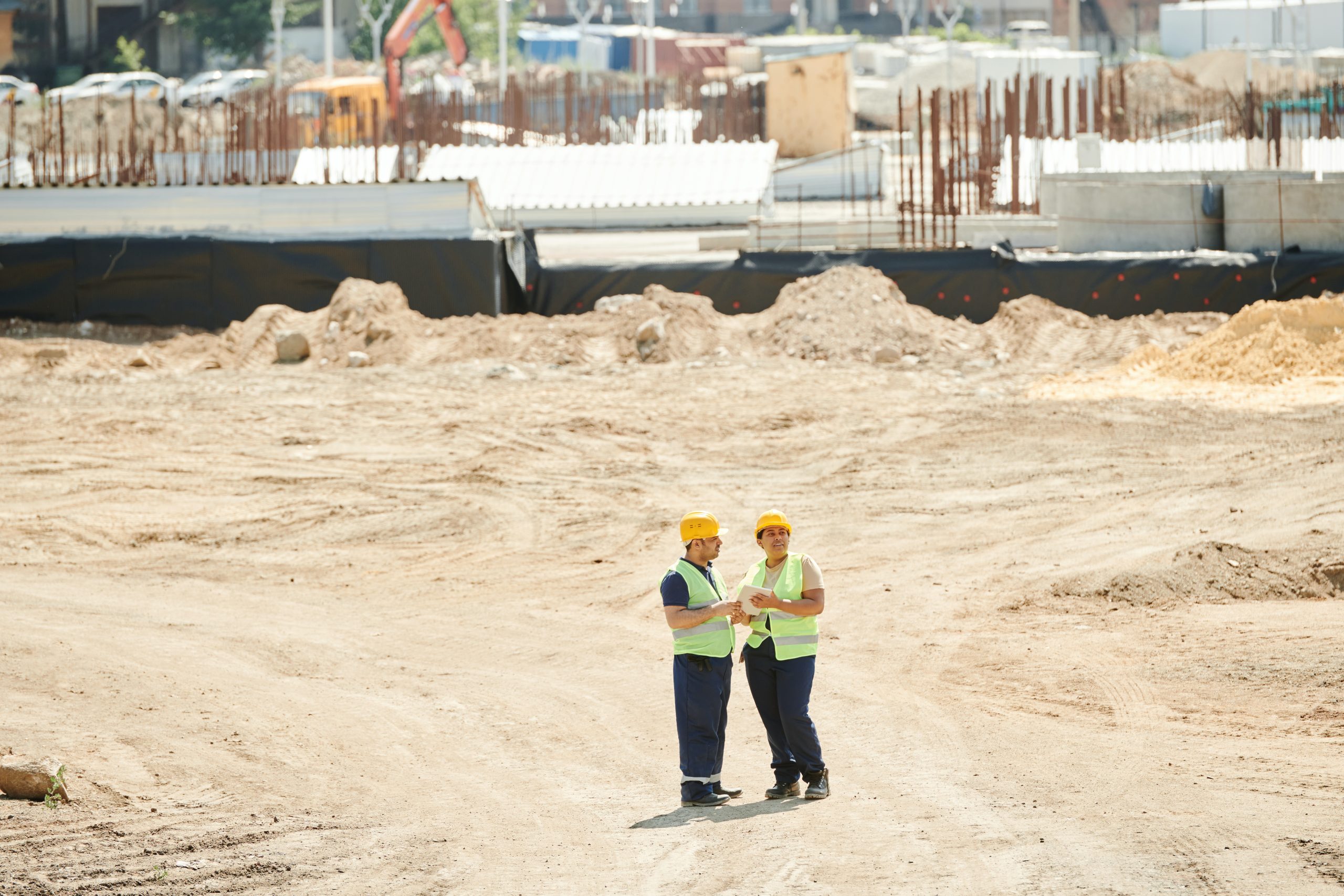 two construction workers standing on sand